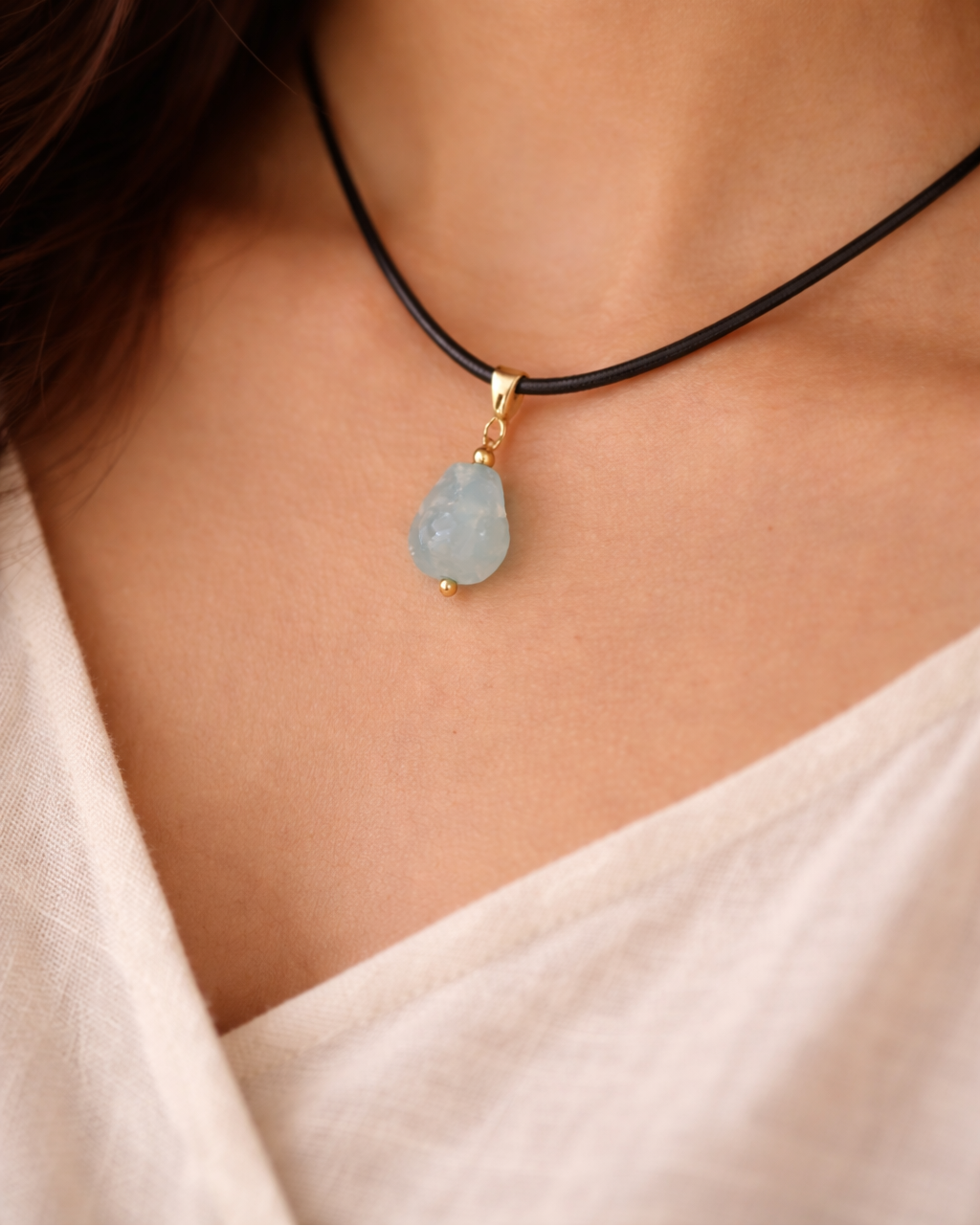 Necklace with a blue pendant on a person wearing a white top