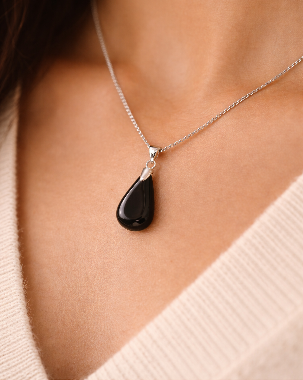 Necklace with a black teardrop pendant worn by a person