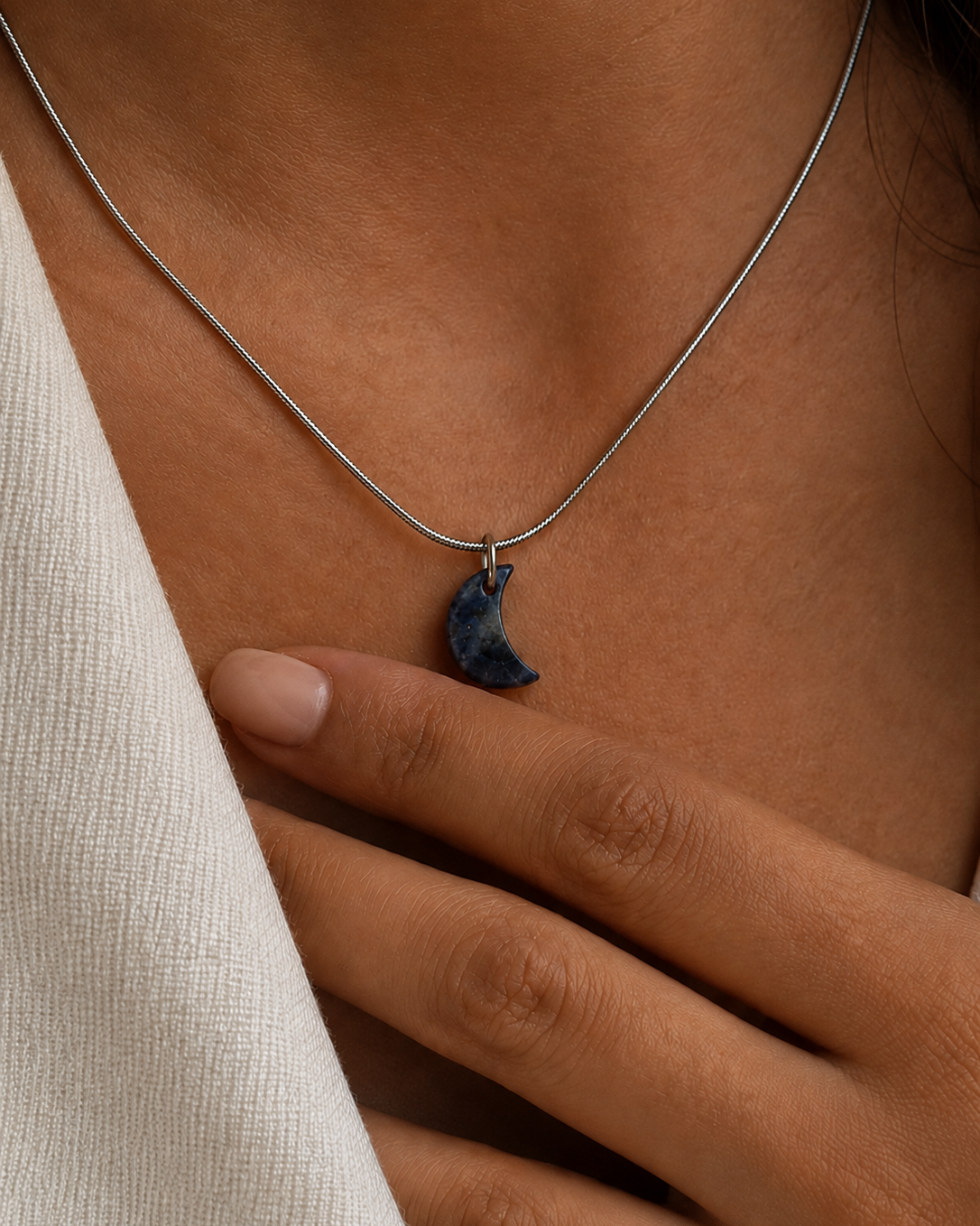 Necklace with a moon-shaped pendant worn by a person