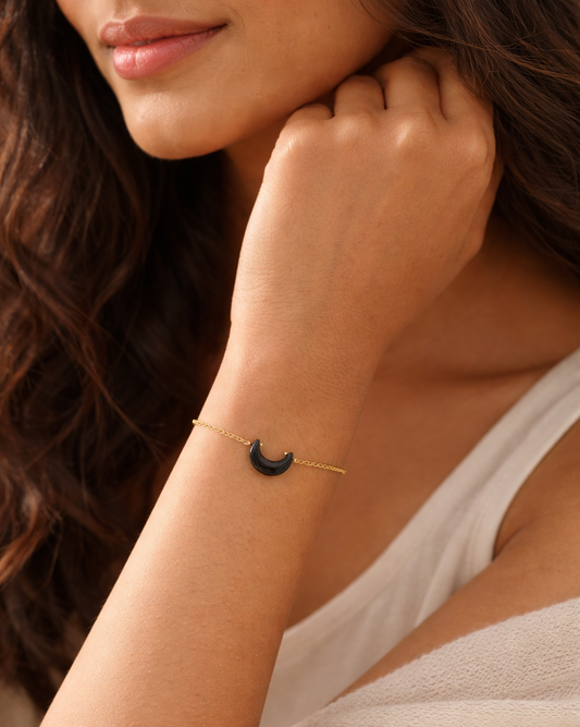 Close-up of a woman wearing a delicate bracelet with a crescent moon charm.