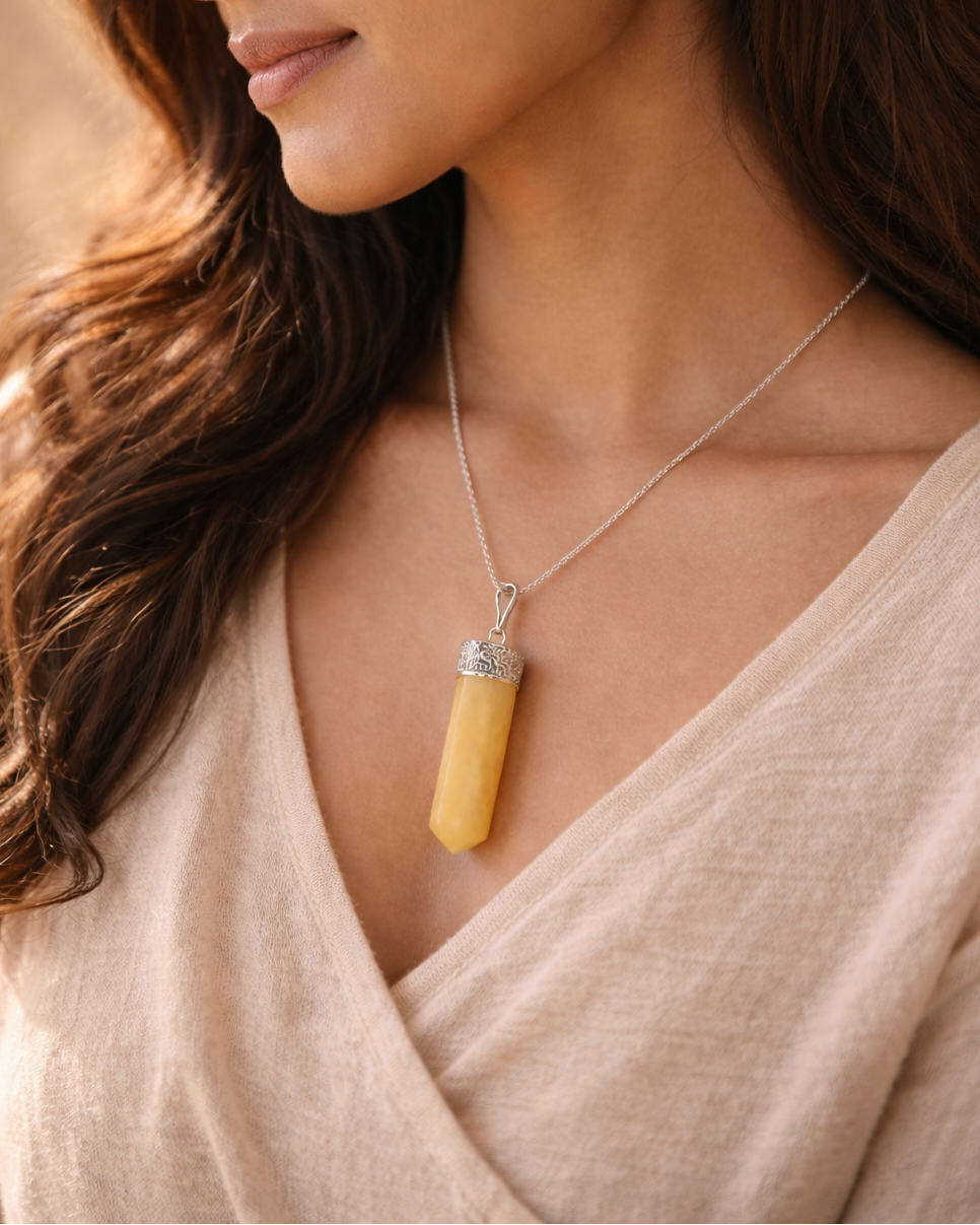 Woman wearing a necklace with a yellow pendant against a neutral background