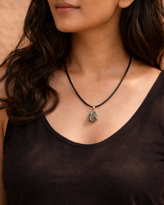 Woman wearing a black tank top and necklace against a brown background