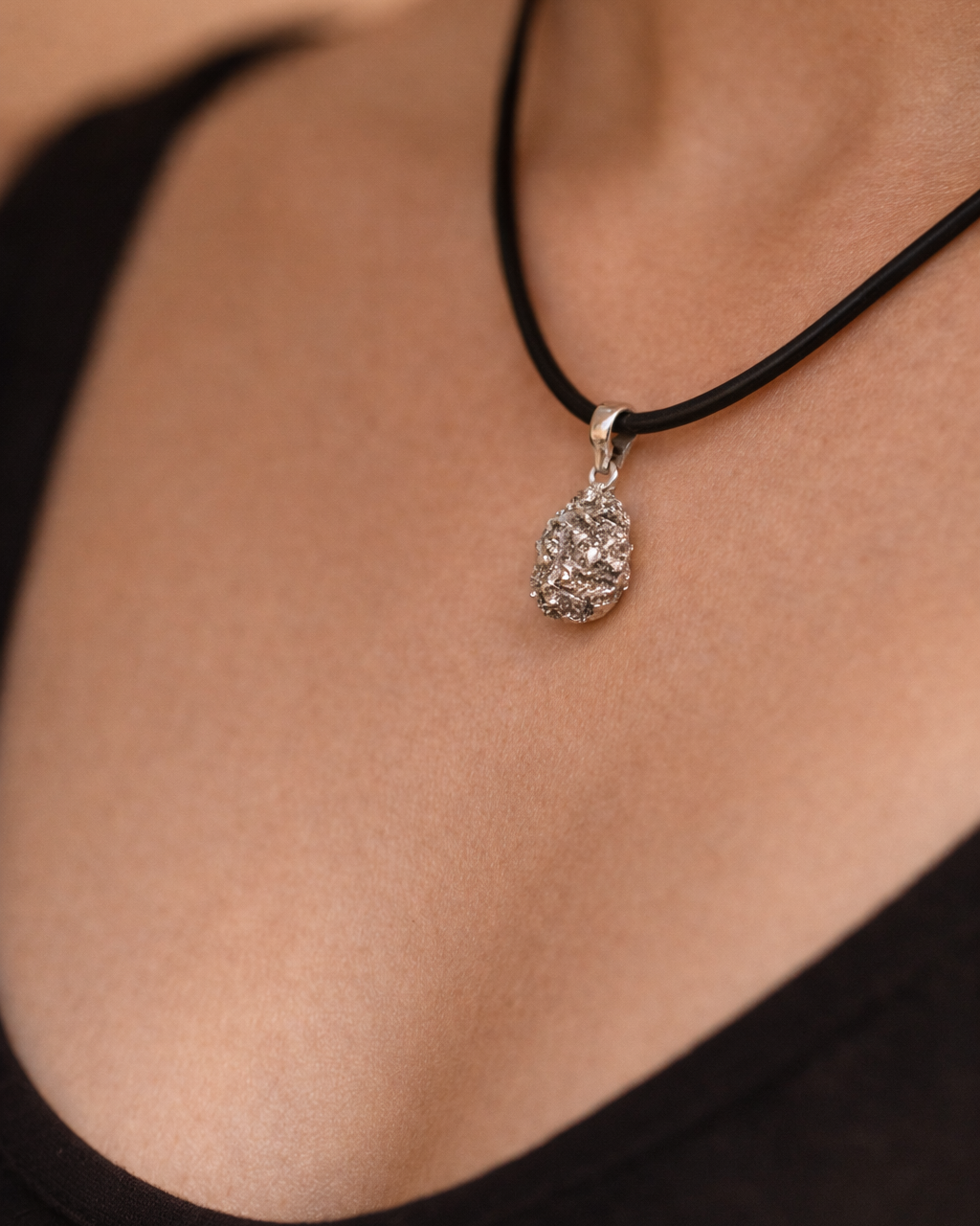 Necklace with a pendant worn by a person, focusing on the jewelry against a neutral background.