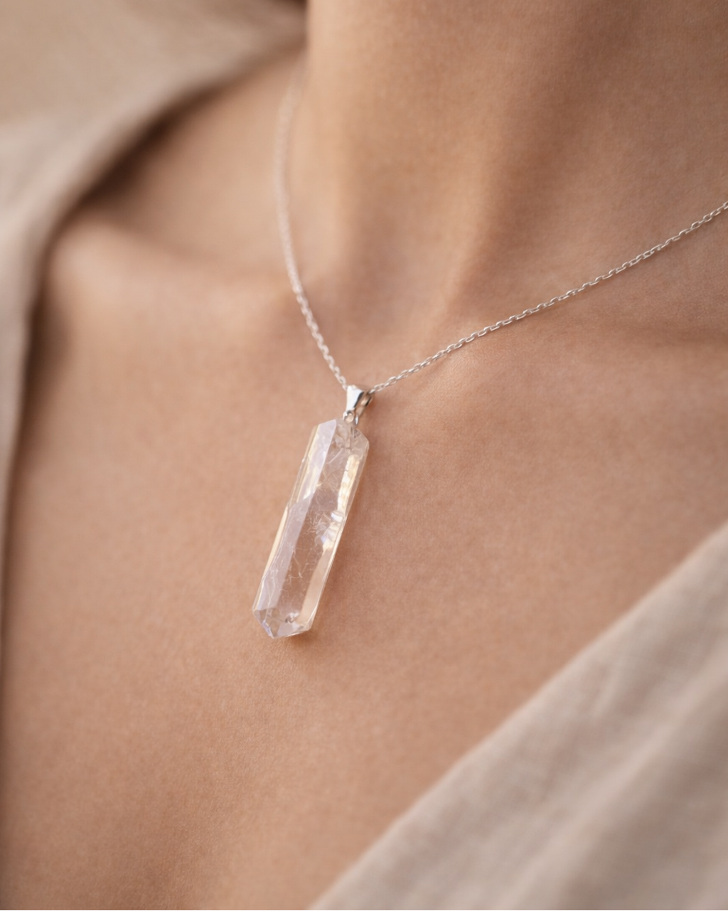Necklace with a clear crystal pendant worn by a person