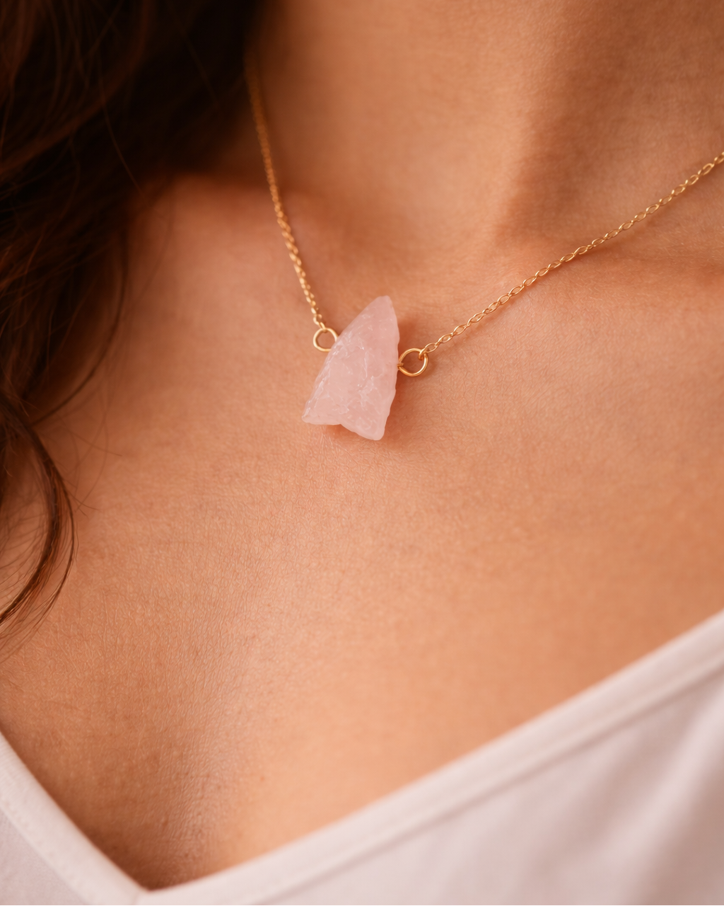 Necklace with a pink stone pendant on a person wearing a white top.