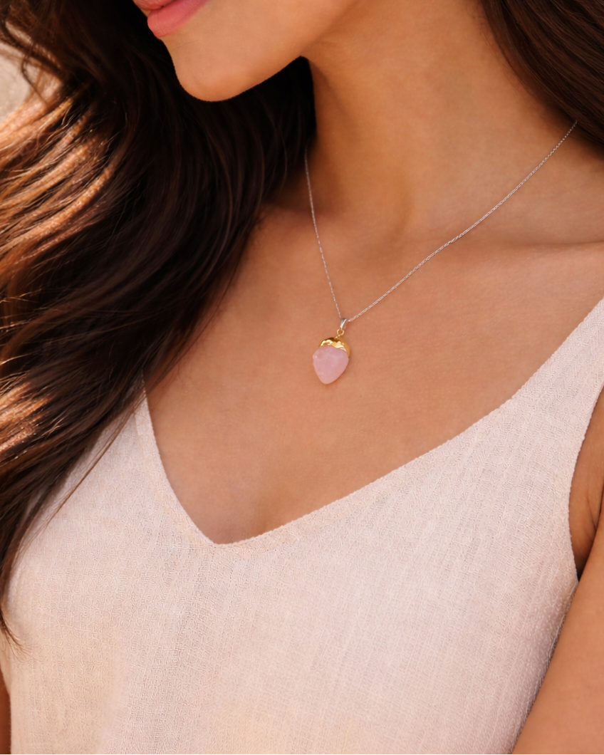 Woman wearing a necklace with a heart-shaped pendant against a neutral background