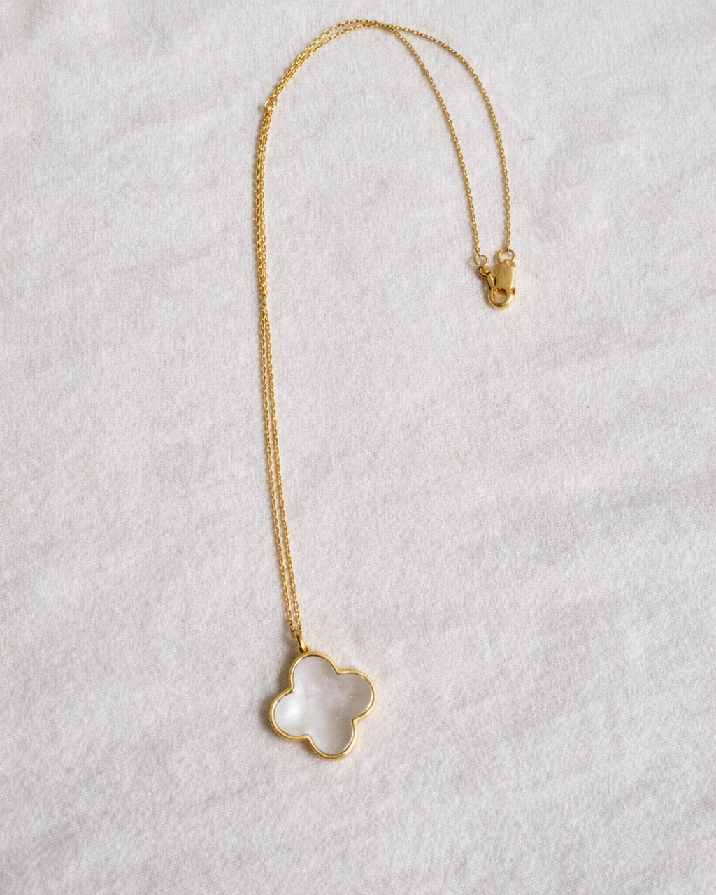 Clear quartz clover pendant with gold chain displayed fully on neutral background, minimal aesthetic jewelry