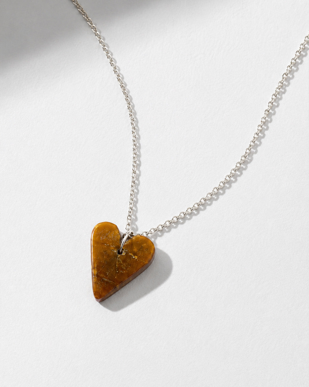 Tiger eye Heart-shaped pendant on a silver chain against a white background