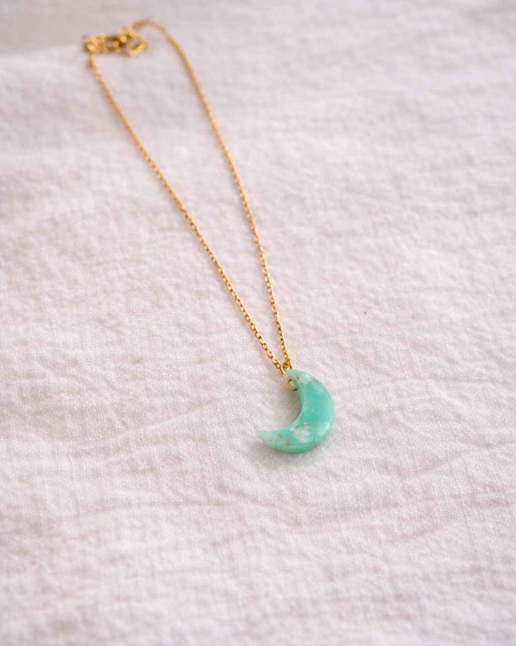 Malachite crescent moon pendant with gold chain displayed on neutral background, minimal aesthetic jewelry style