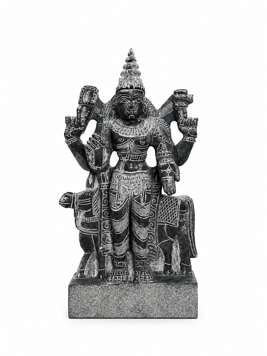 A dark gray stone statue of a multi-armed Hindu deity, likely Shiva, standing on a rectangular base against a plain white background.