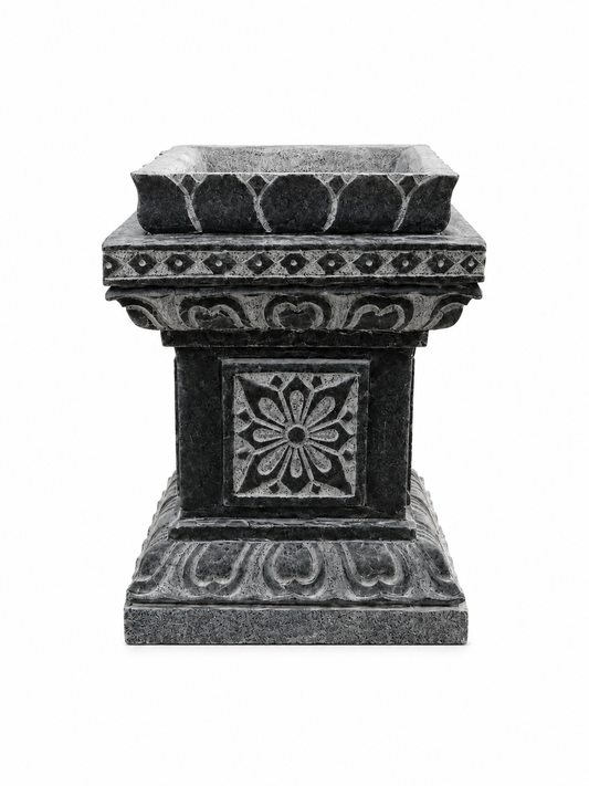 A dark gray stone planter pedestal with ornate carved floral and geometric patterns, isolated on a white background.