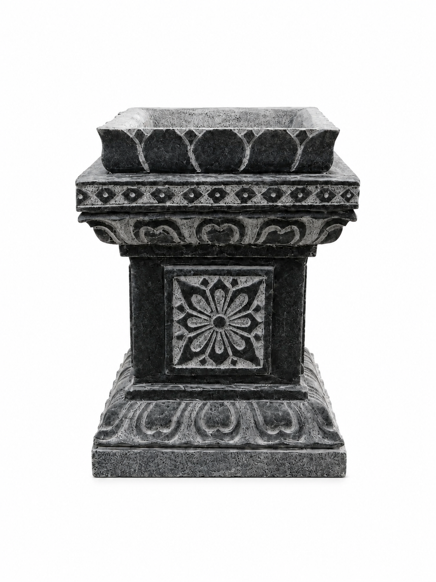 A dark gray stone planter pedestal with ornate carved floral and geometric patterns, isolated on a white background.