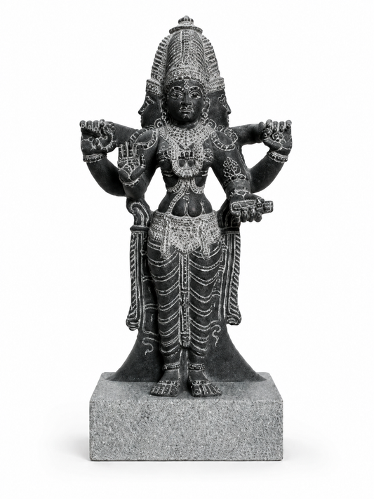 A dark gray stone statue of a four-armed Hindu deity, standing on a square stone base against a plain white background.