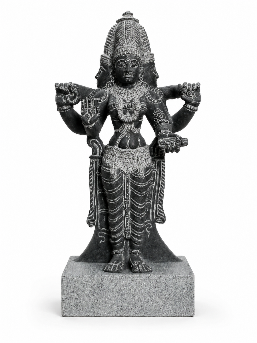A dark gray stone statue of a four-armed Hindu deity, standing on a square stone base against a plain white background.