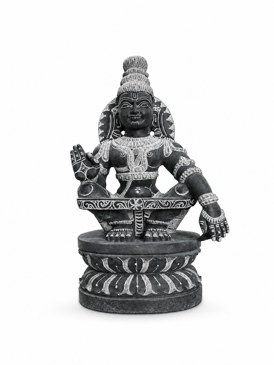 A dark gray stone statue of a Hindu deity seated on a lotus pedestal, featuring detailed light-colored carvings and a serene expression, isolated on a white background.