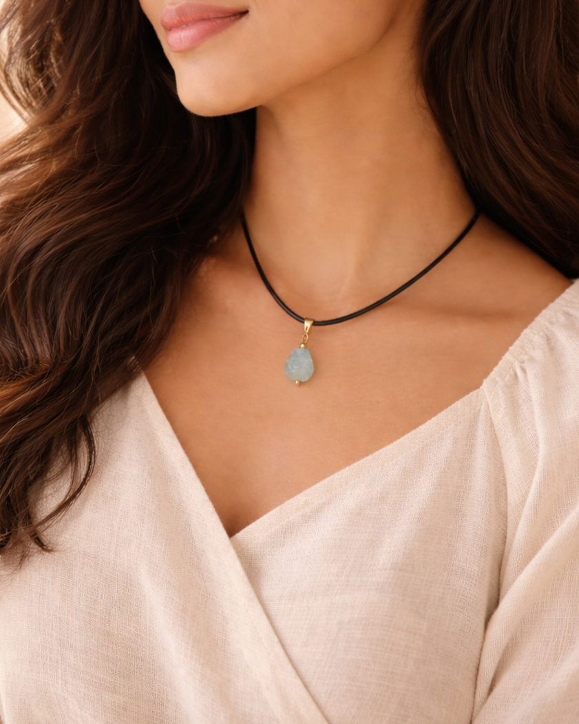 Woman wearing a necklace with a beige top against a soft background