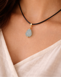 Necklace with a blue pendant on a person wearing a white top
