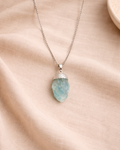 Aquamarine pendant with stainless steel chain on beige background