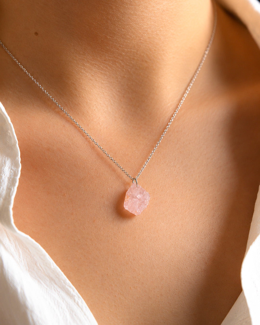 Raw Rose Quartz Necklace with a pink stone pendant on a person wearing a white top.