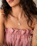 Close-up of a woman wearing a pink top and a Clear Quartz necklace with a pendant.
