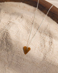 Tiger Eye Heart-shaped pendant necklace on a wooden surface with sand