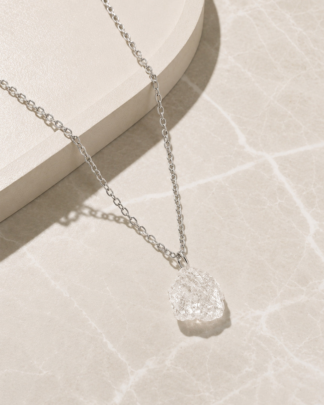 Silver Clear Quartz necklace with a textured pendant on a light background