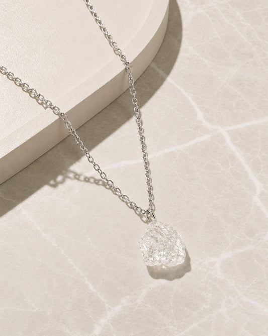Silver Clear Quartz necklace with a textured pendant on a light background