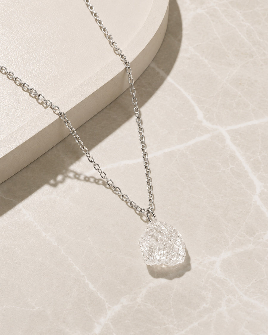 Silver Clear Quartz necklace with a textured pendant on a light background