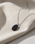 Lapis Lazuli Necklace with a teardrop-shaped pendant on a textured beige surface