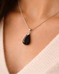 Necklace with a black teardrop pendant worn by a person