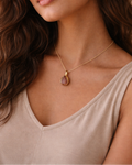 Woman wearing a necklace with a pendant against a neutral background