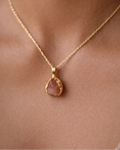 Gold necklace with a brown pendant on a person's neck
