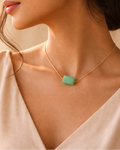 Woman wearing a gold necklace with a green pendant