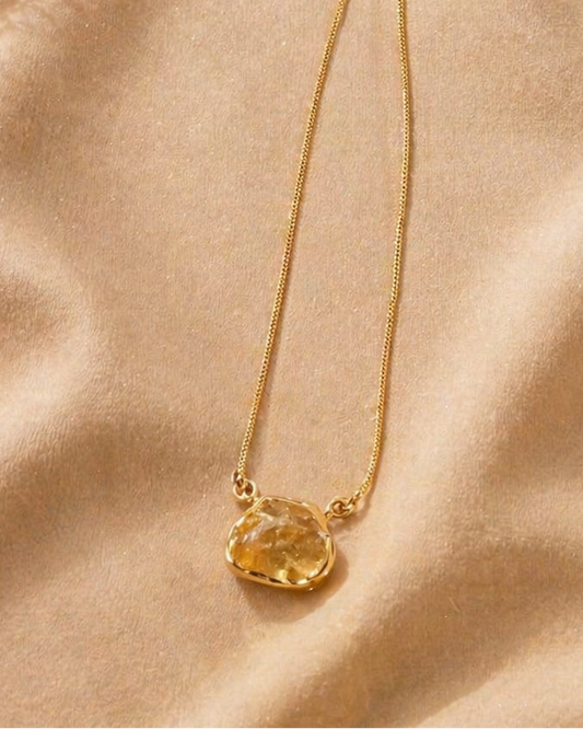 Gold necklace with a pendant on a beige fabric background