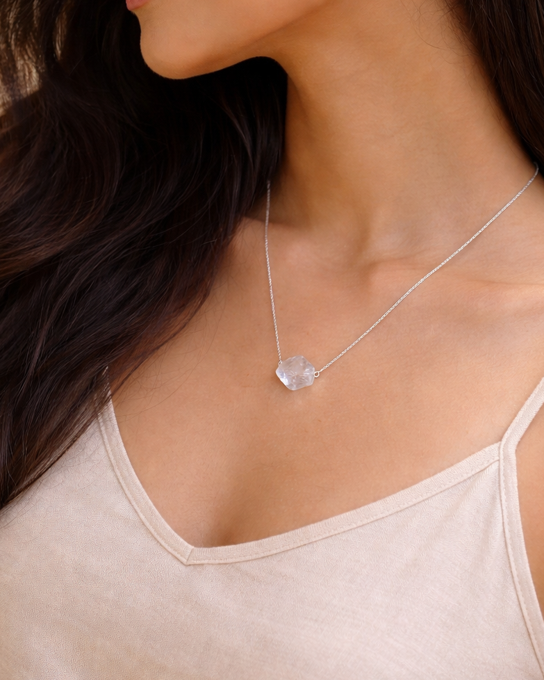 Woman wearing a delicate necklace with a heart-shaped pendant.