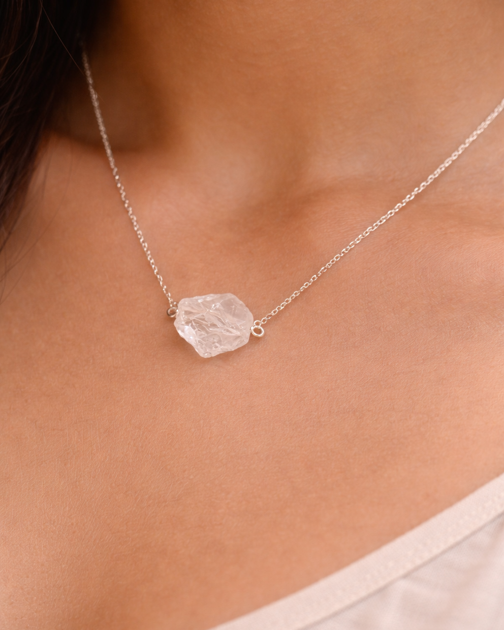Necklace with a clear crystal pendant worn by a person