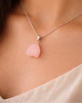 Necklace with a pink pendant on a person wearing a light-colored top.