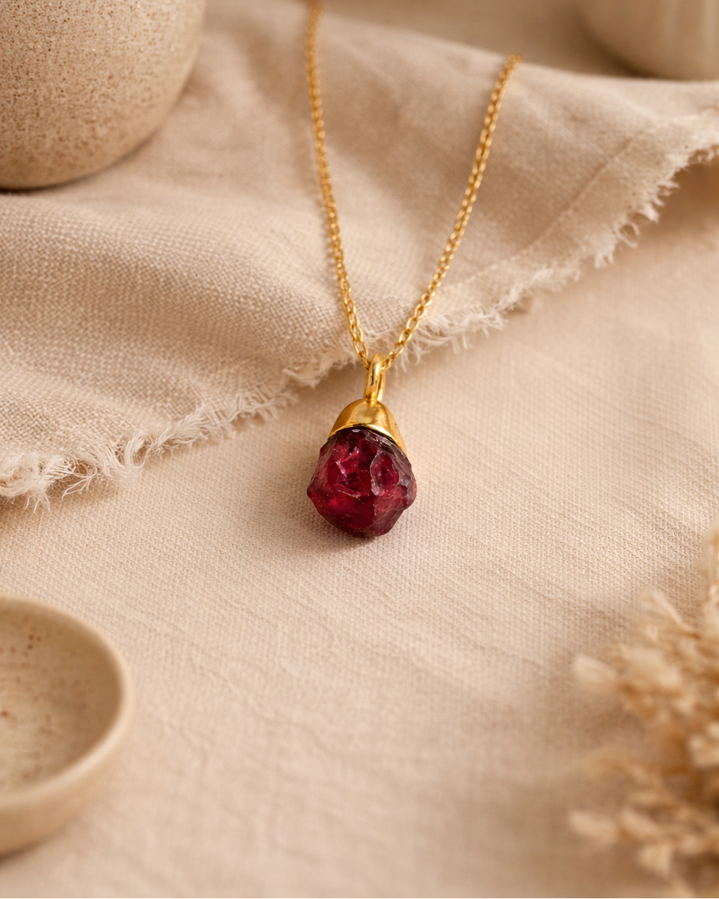Raw garnet gold plated necklace on beige aesthetic background