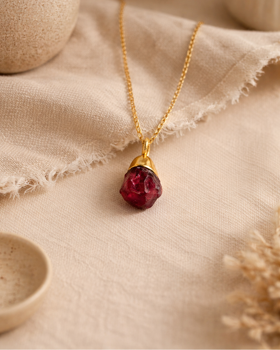 Raw garnet gold plated necklace on beige aesthetic background