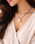 Woman wearing a necklace with a pink pendant against a neutral background