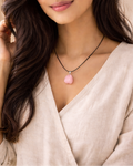 Woman wearing a necklace with a pink pendant against a neutral background