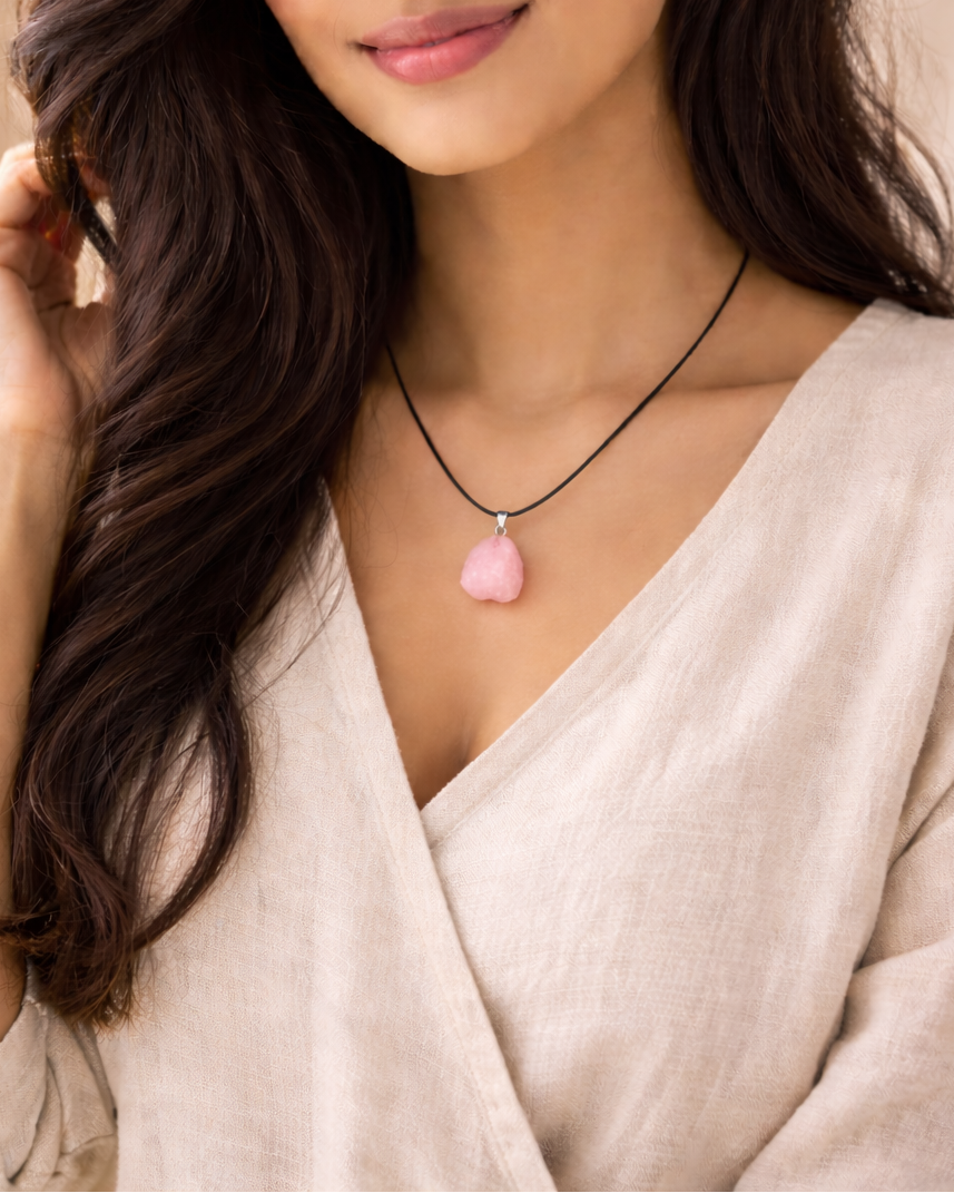 Woman wearing a necklace with a pink pendant against a neutral background