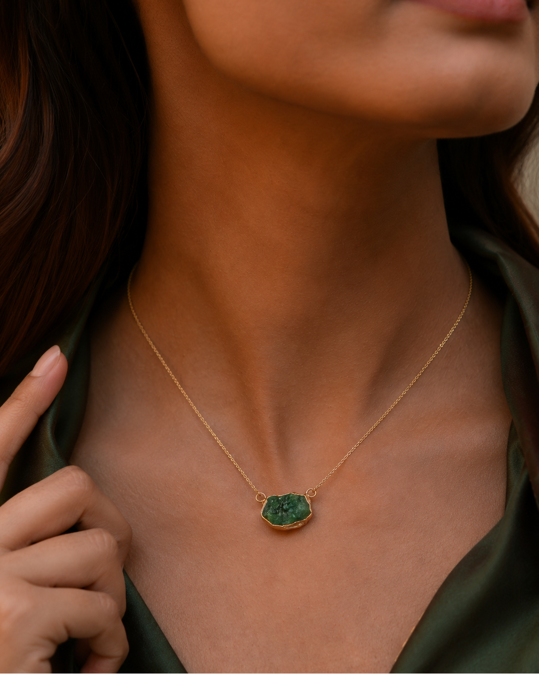 Close-up of a person wearing a gold necklace with a green pendant.