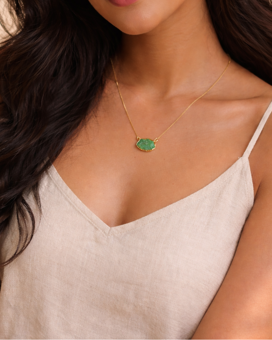 Woman wearing a necklace with a green pendant against a neutral background
