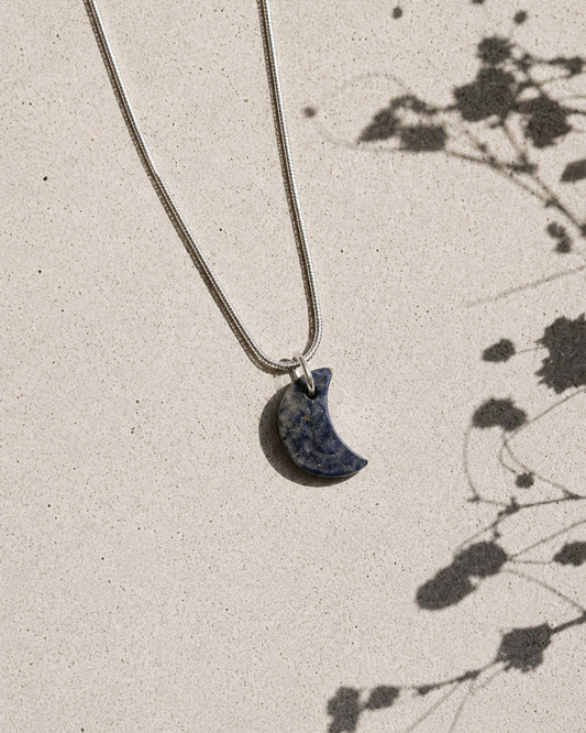 Necklace with a moon-shaped pendant on a light background