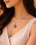 Woman wearing a necklace with a blue and silver pendant