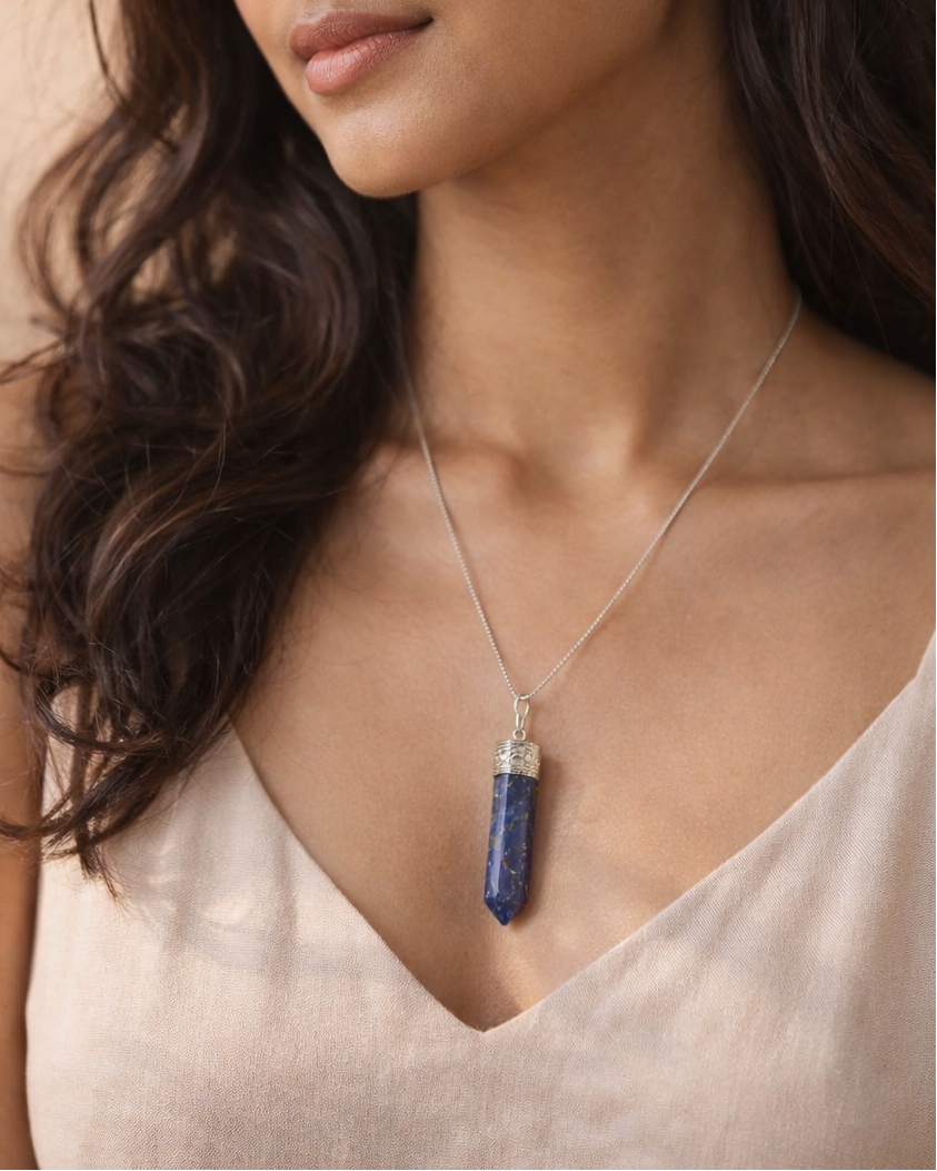Woman wearing a necklace with a blue pendant against a beige background