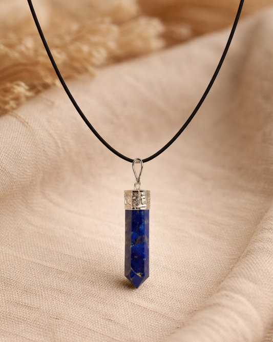 Blue crystal pendant on a black cord against a beige fabric background