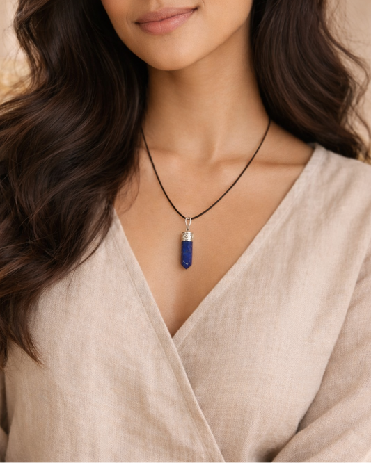 Woman wearing a necklace with a blue pendant against a neutral background