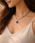 Woman wearing a necklace with a blue pendant against a neutral background